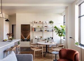 A modern, well-lit room with a dining table, chairs, and a large window.