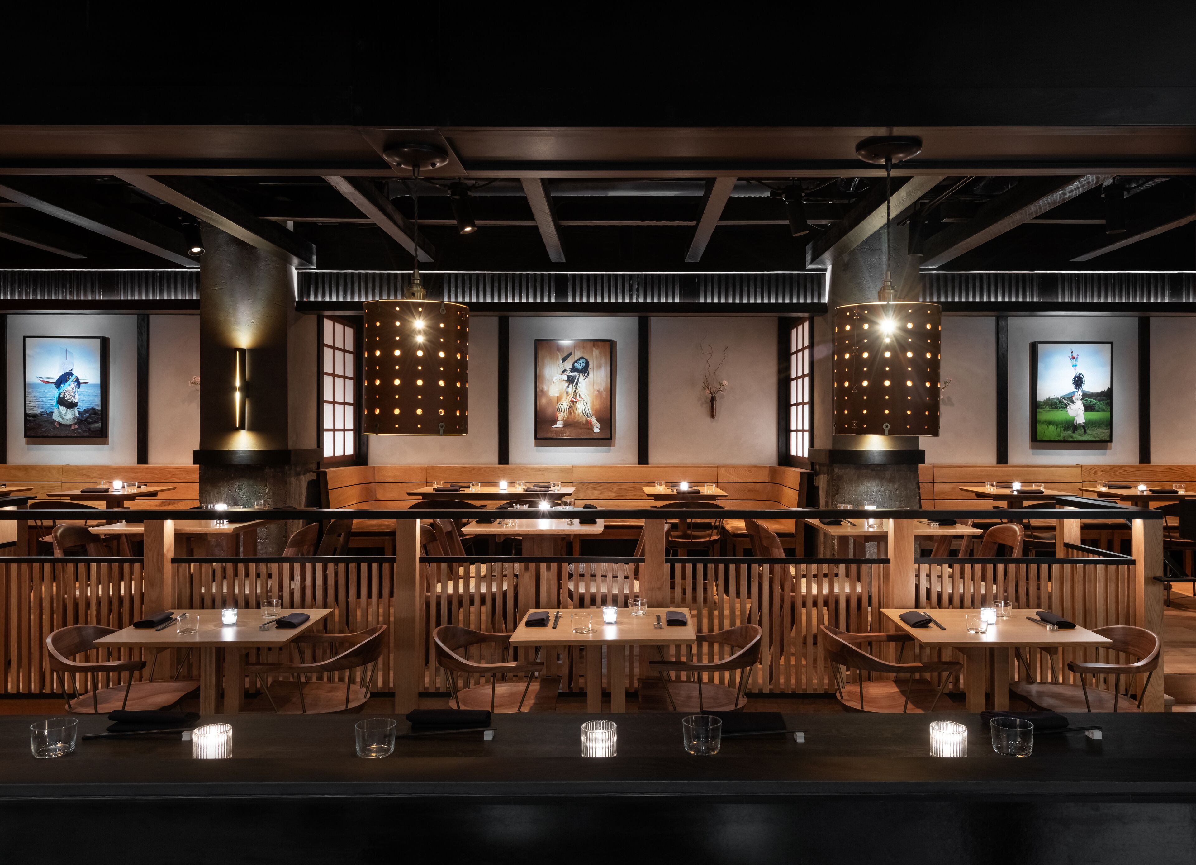 A restaurant with wooden booths and tables, pendant lighting, and artwork on the walls.