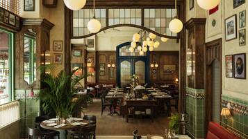 A spacious restaurant with high ceilings, wooden beams, and multiple dining tables and booths.