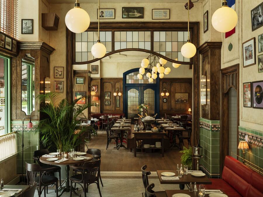 A spacious restaurant with high ceilings, wooden beams, and multiple dining tables and booths.