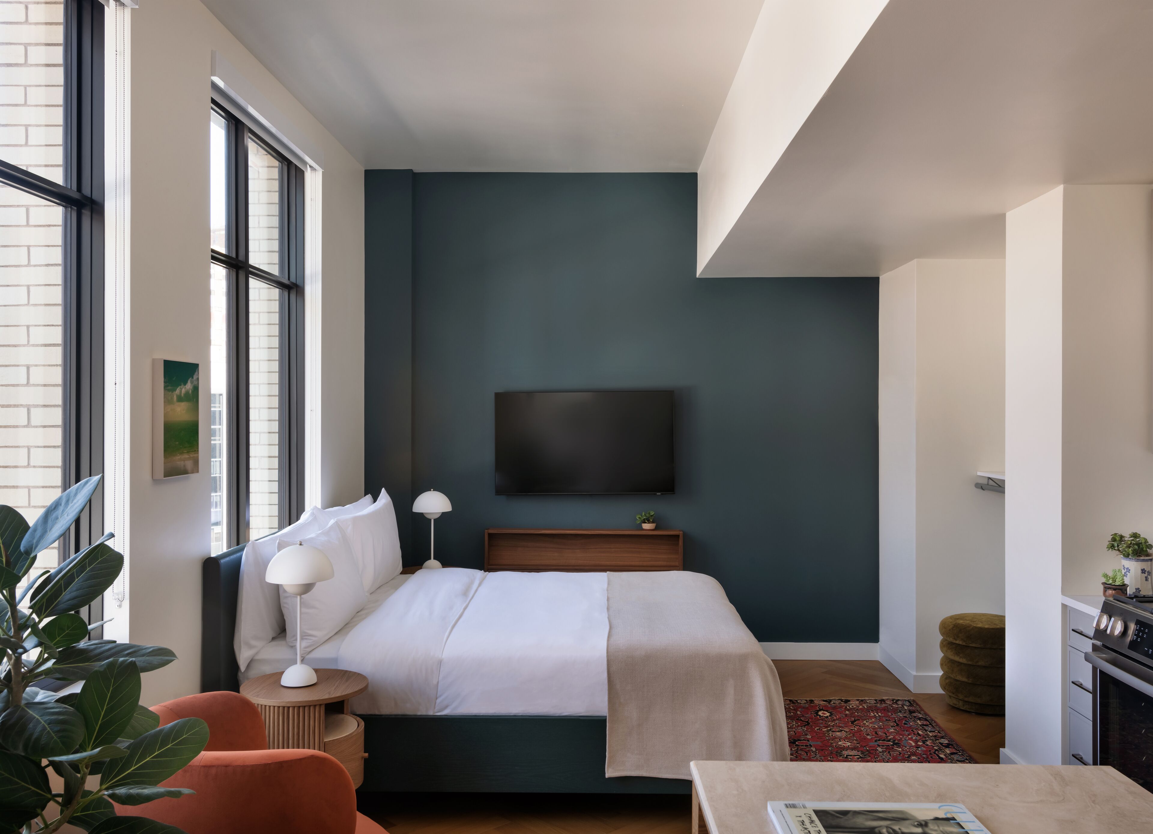 A modern hotel room with a large bed, a flat-screen TV mounted on the wall, a small table, and a chair.