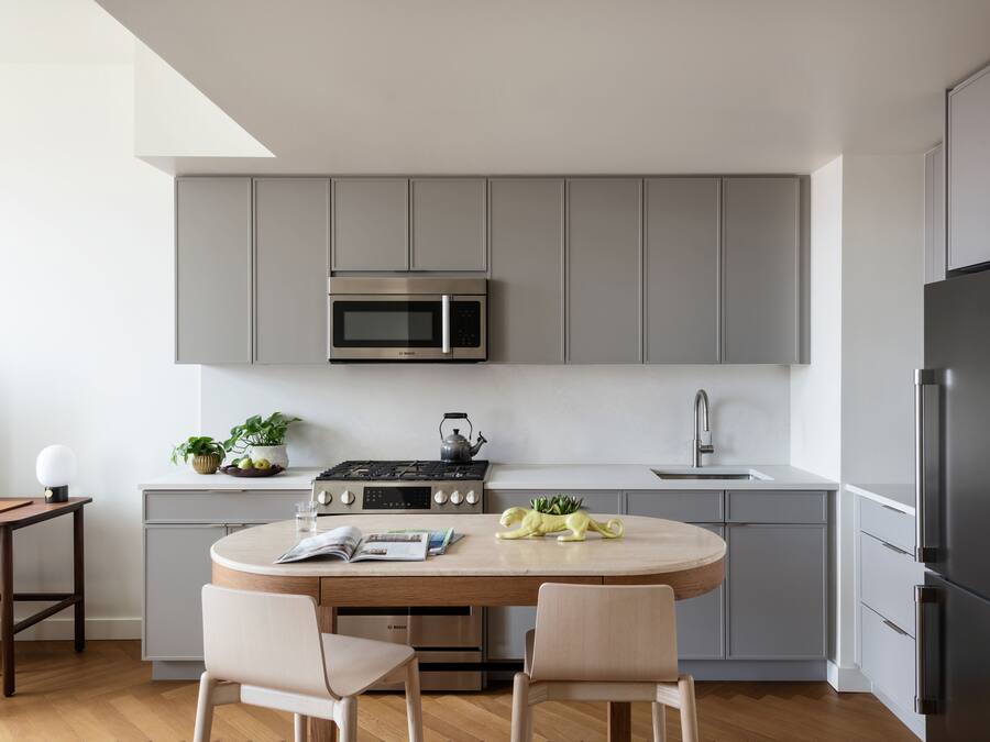 A modern kitchen with grey cabinets, a Bosch gas stove, a microwave, and a refrigerator.