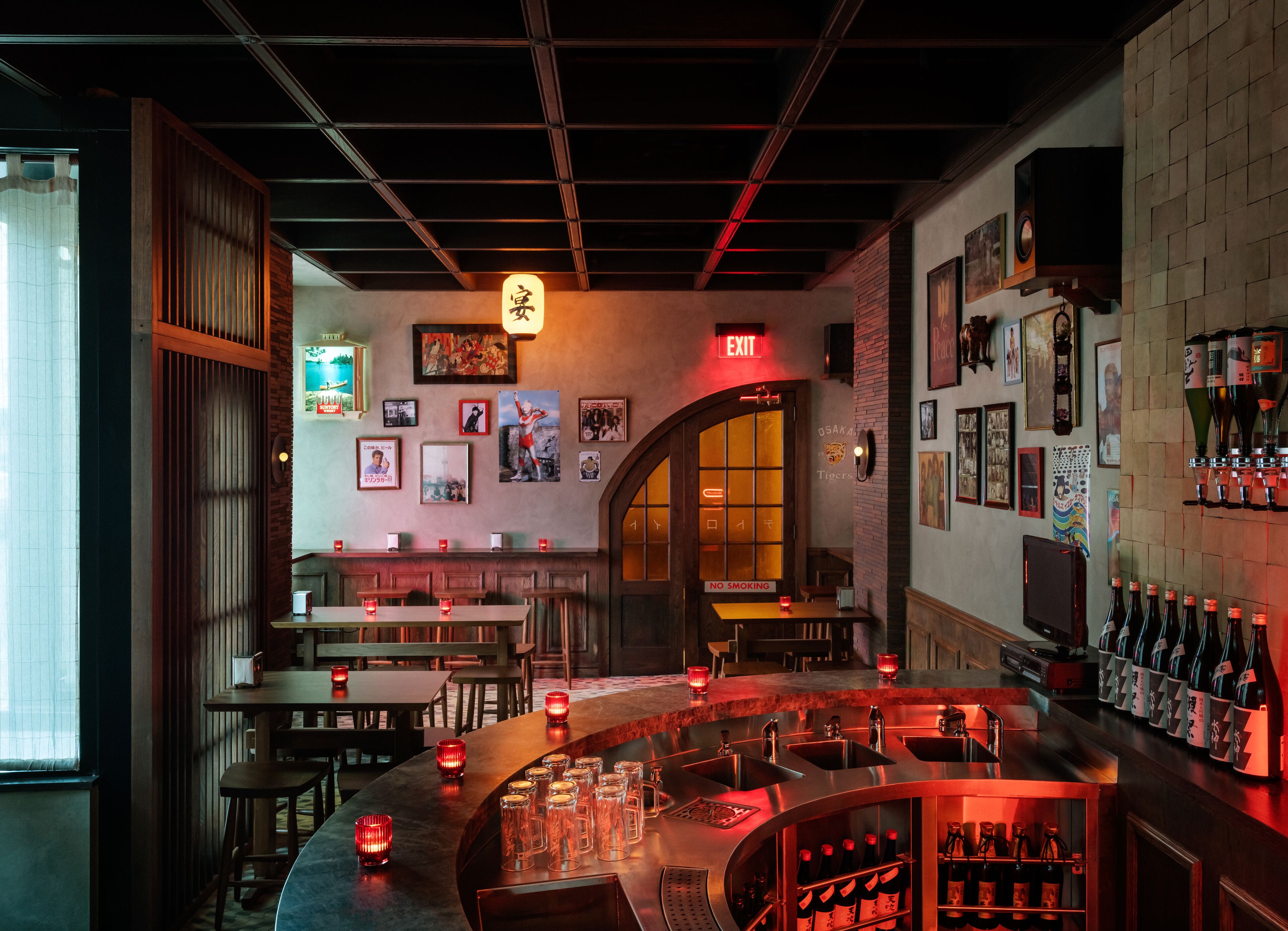 A bar area with multiple seating options, a visible exit sign, and a wall adorned with various framed pictures.