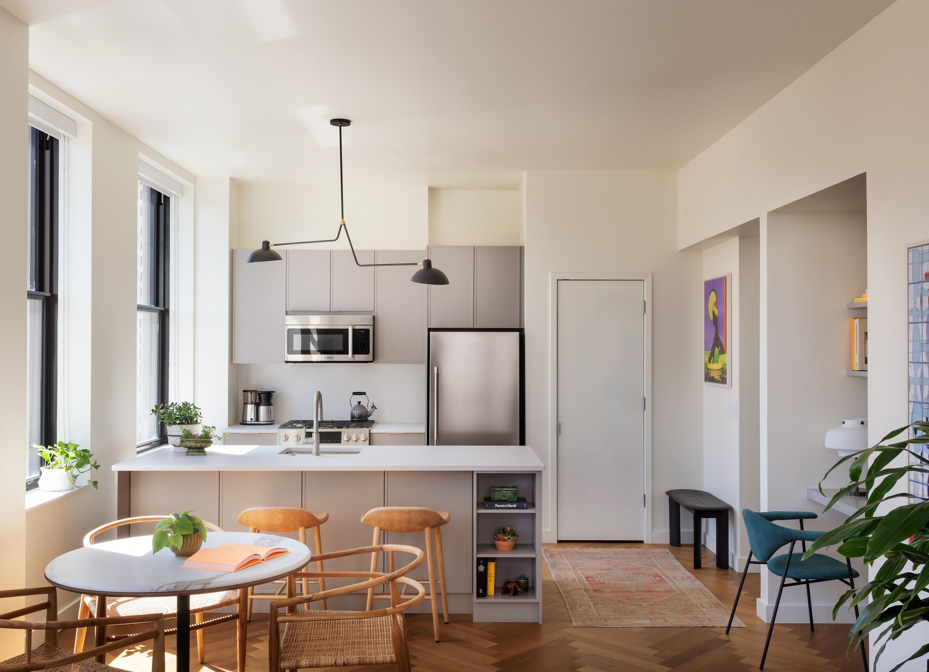 Una cocina moderna con una isla central, electrodomésticos de acero inoxidable y sillas de madera.