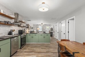 Une cuisine moderne avec des meubles de couleur verte, une table à manger en bois et un îlot central.