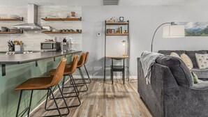 Ett modernt kök med barstolar, ett matbord och ett mysigt vardagsrum med en soffa och en lampa.