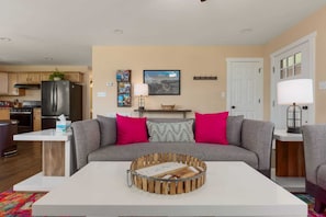 A living room with a gray sofa, a coffee table, and a wooden crate with a nameplate.