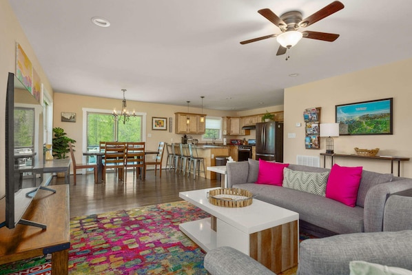 A spacious living room with a gray sofa, colorful rug, and a ceiling fan.