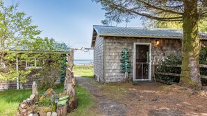 Une cabane en bois rustique, dotée d’un toit en métal, d’une porte et d’un petit porche.
