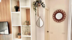 Una zona de menjador moderna amb una taula blanca, cadires i un mirall decoratiu a la paret.