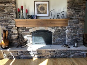 Cozy fireplace features a mantel with candles, artwork, and decorative accents.