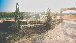 A sign for Ozark Mountain Adventure with a dirt path leading to a wooden structure.