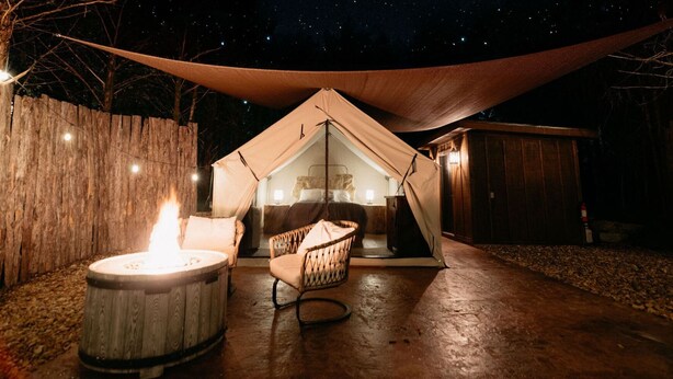 A tented accommodation with a fire pit and seating area.