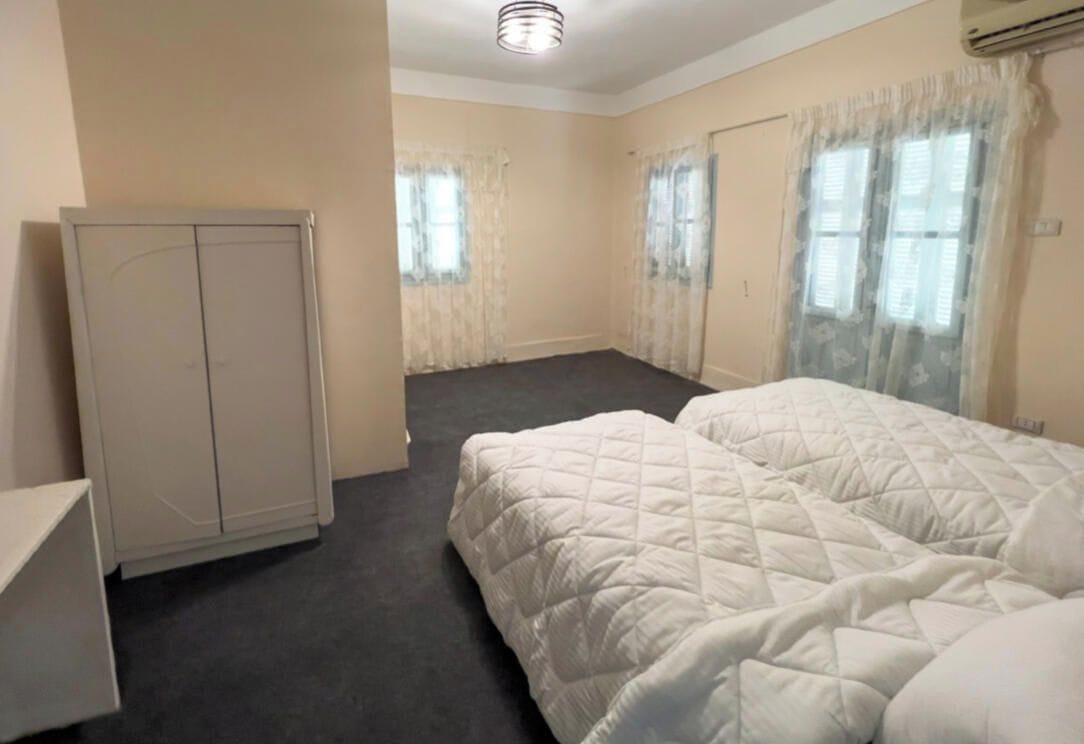 A room with two beds, a wardrobe, and a door.