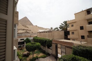 Un patio con vista a la pirámide, rodeado de edificios con balcones y antenas parabólicas.