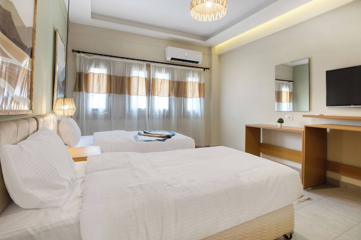 Une chambre d’hôtel avec deux lits, un bureau, une télévision et un appareil de climatisation.