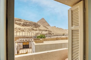 A view of the Great Pyramid of Giza through a window with closed blinds.