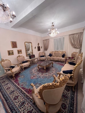 A room with ornate furniture, a chandelier, and a large mirror.