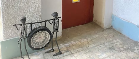 A hallway with a wheelchair, a door with a yellow light, and a textured wall.