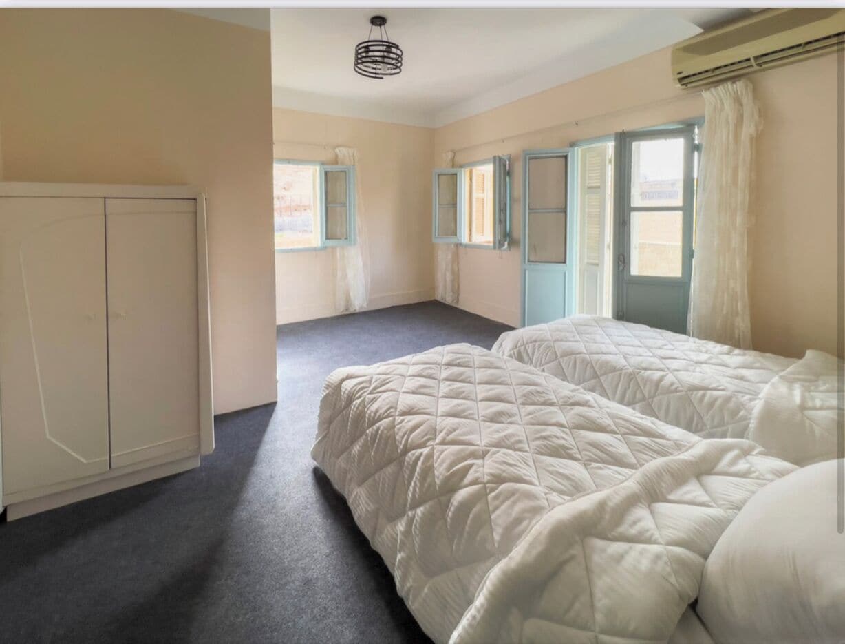 Een kamer met twee bedden, een kledingkast en een raam met gordijnen.