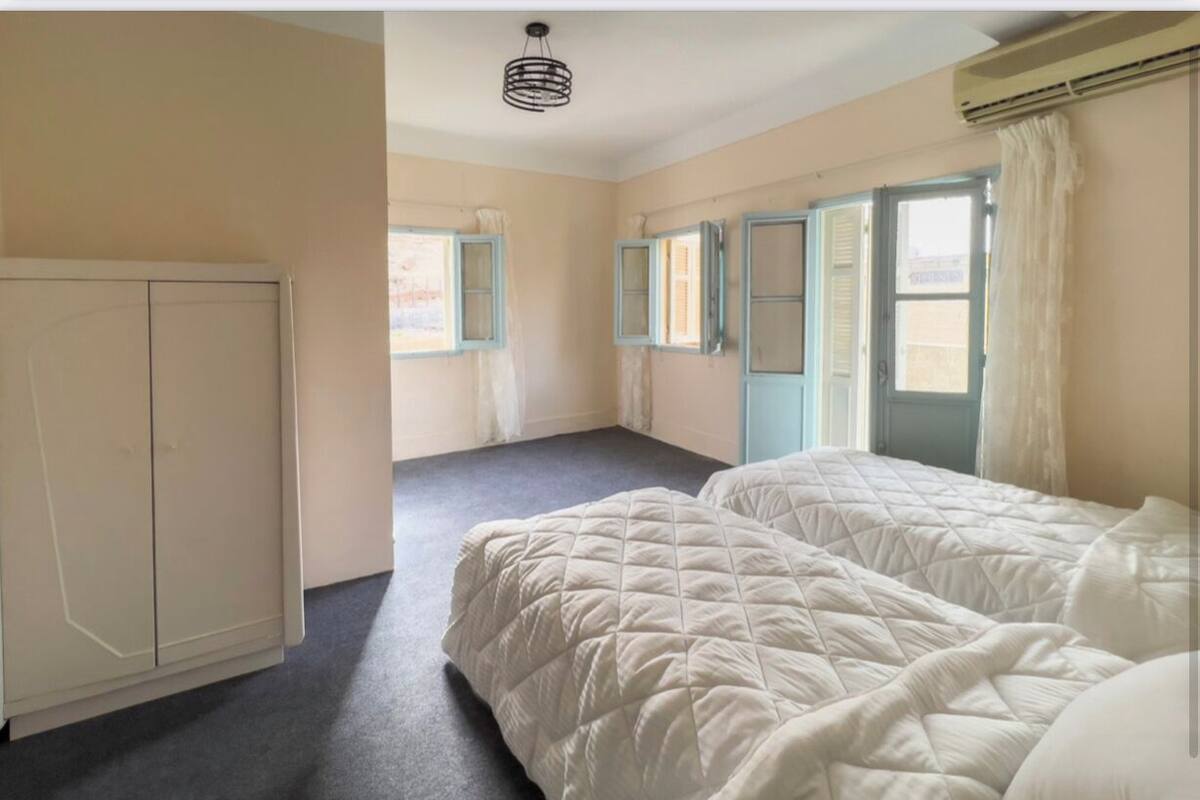Une chambre avec deux lits, une armoire et une fenêtre avec des rideaux.