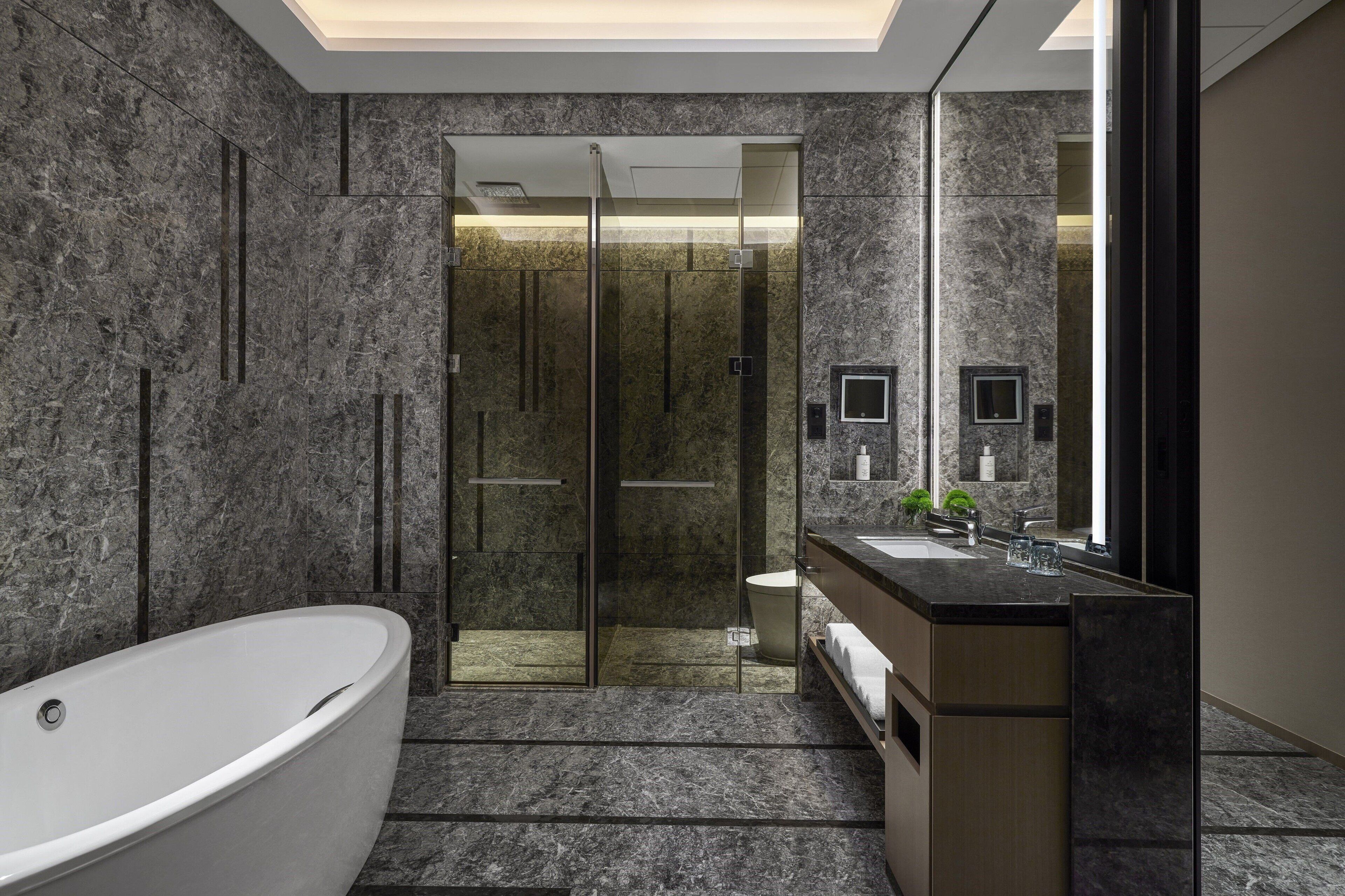 A modern bathroom with a freestanding bathtub, a glass shower enclosure, and a vanity with a mirror.