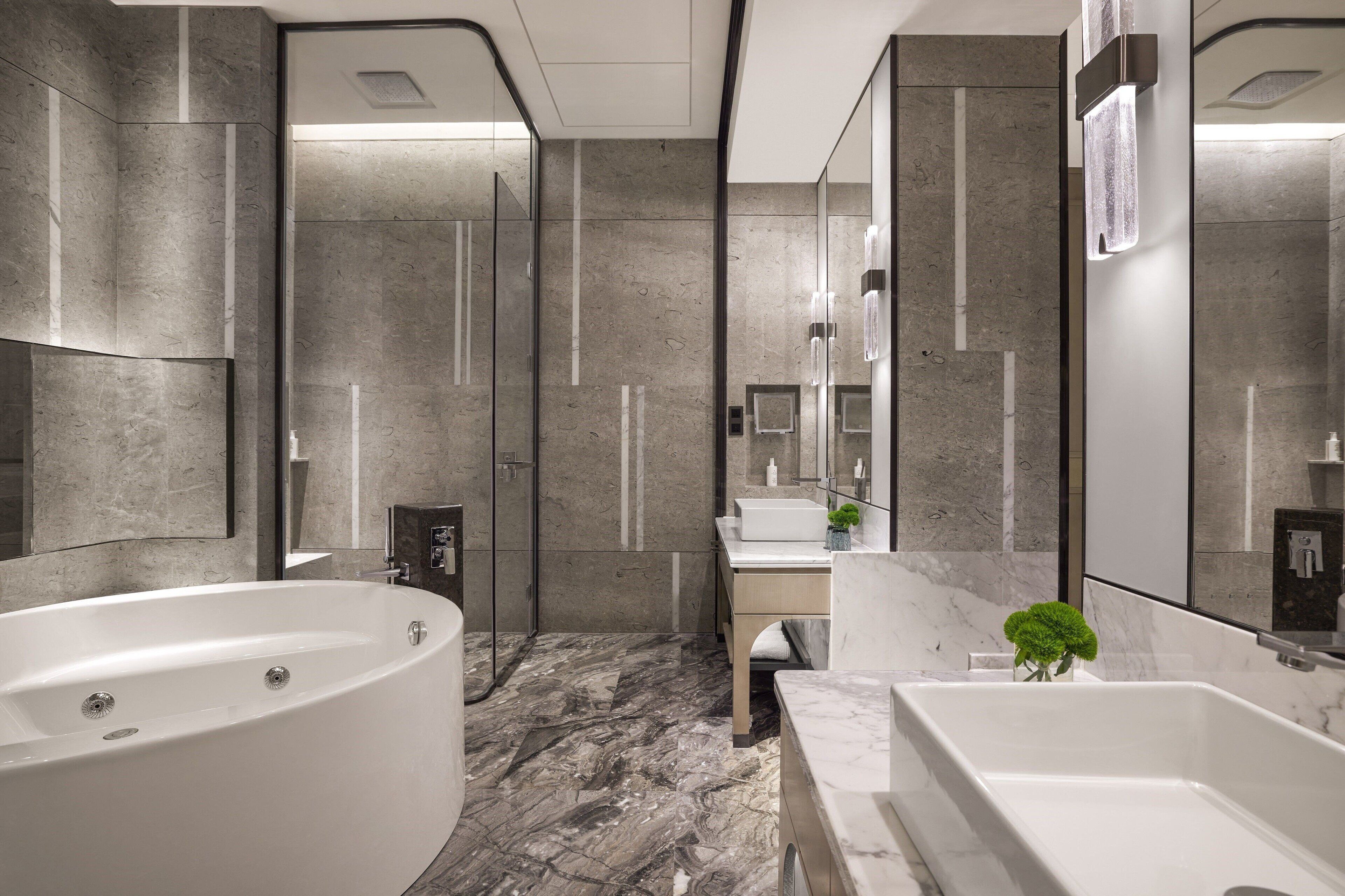 A modern bathroom with a large bathtub, a shower area, and a vanity with a mirror.