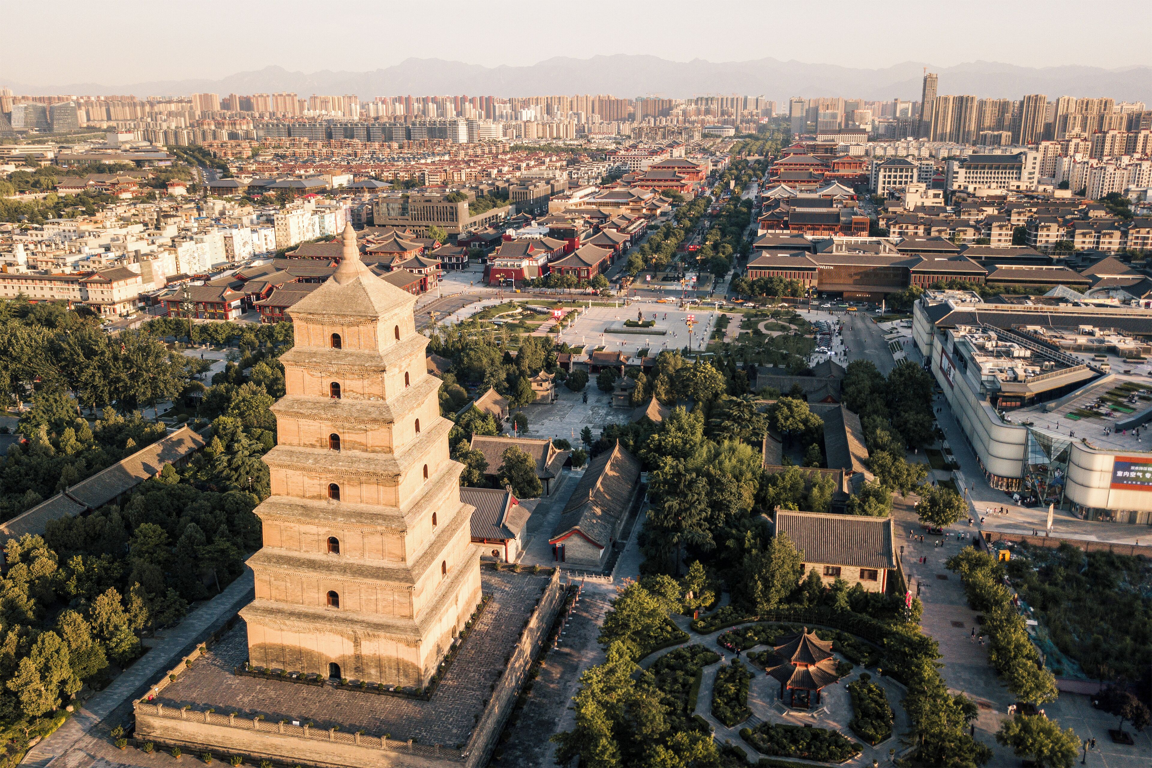 Una torre histórica rodeada de edificios tradicionales y un paisaje urbano moderno.
