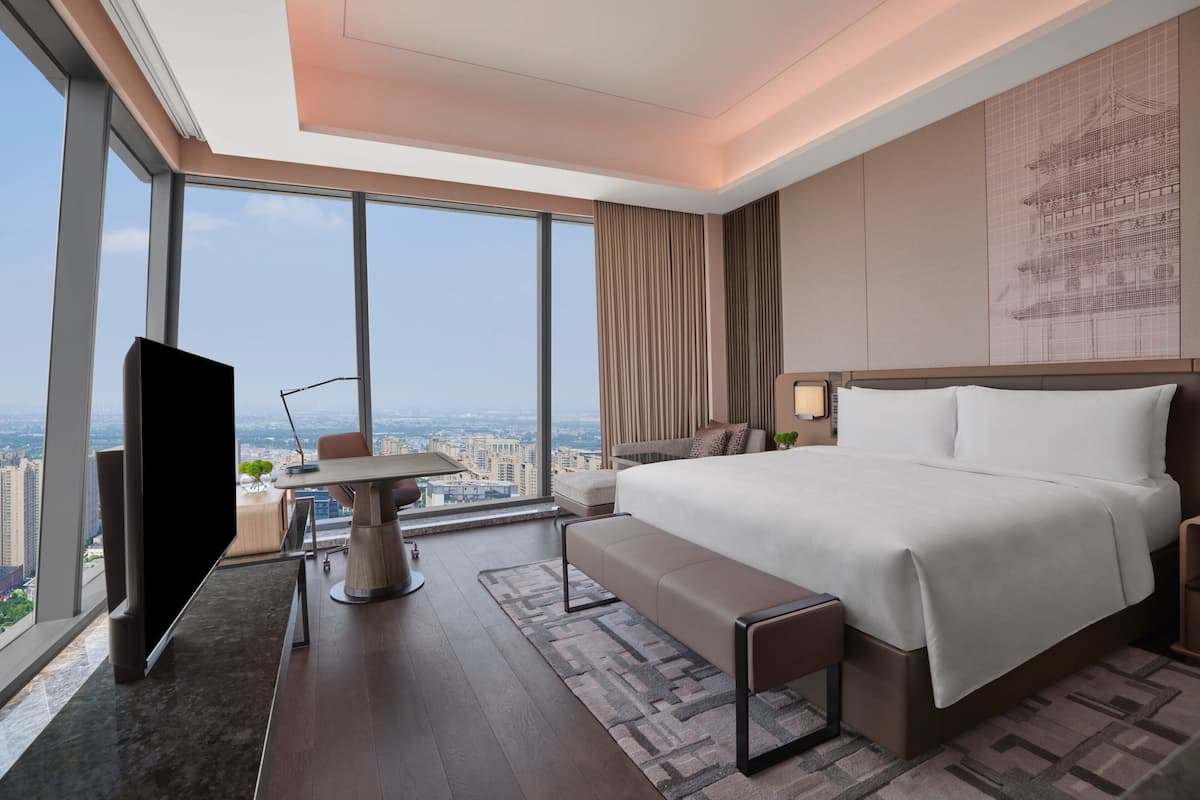 A modern hotel room with a large bed, a desk, and a TV.