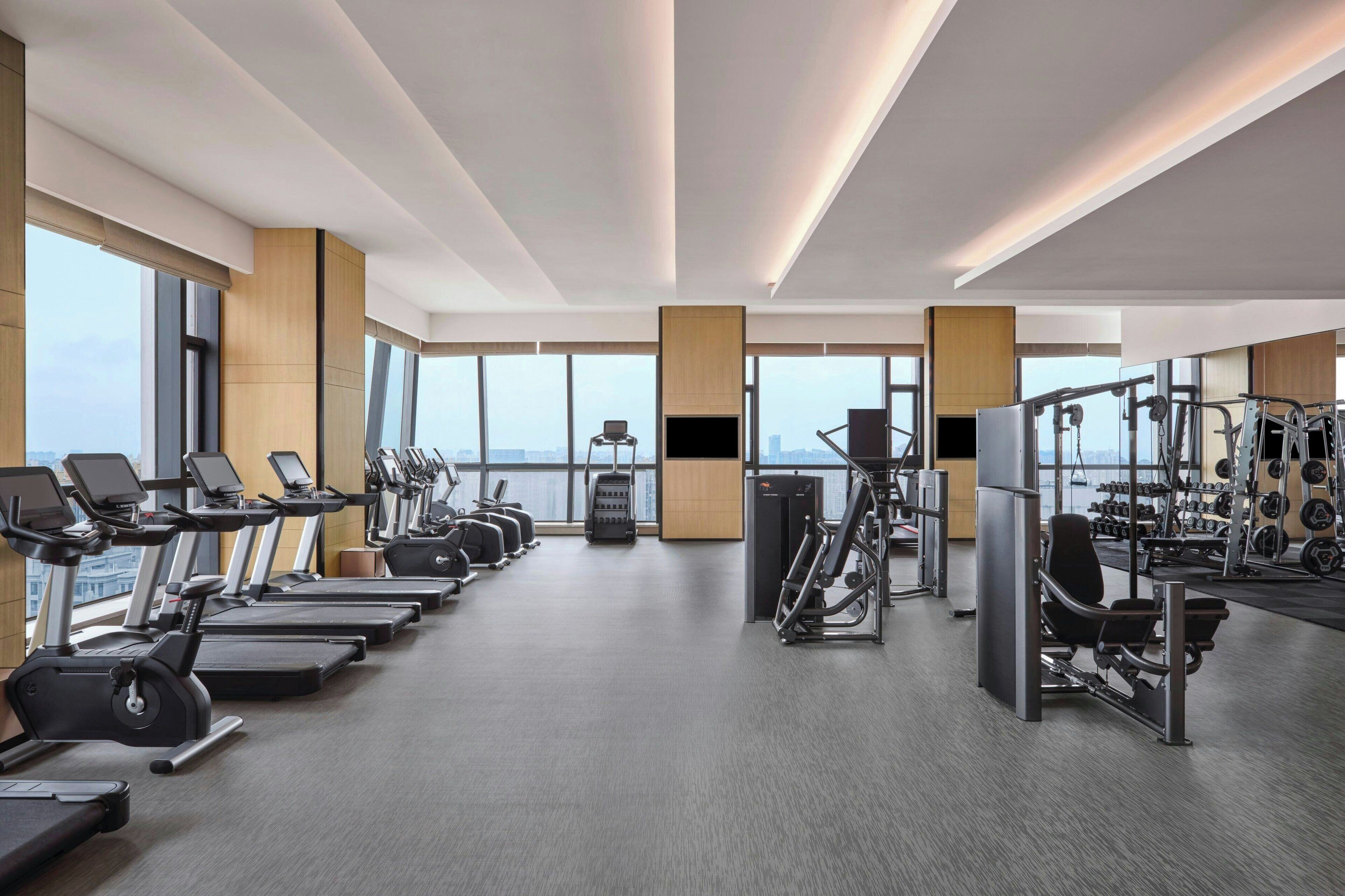 A modern gym with treadmills, elliptical machines, and weightlifting equipment.