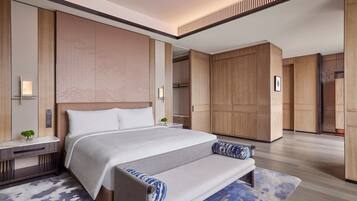 A modern hotel room with a large bed, bedside tables, a bench, and a wardrobe.