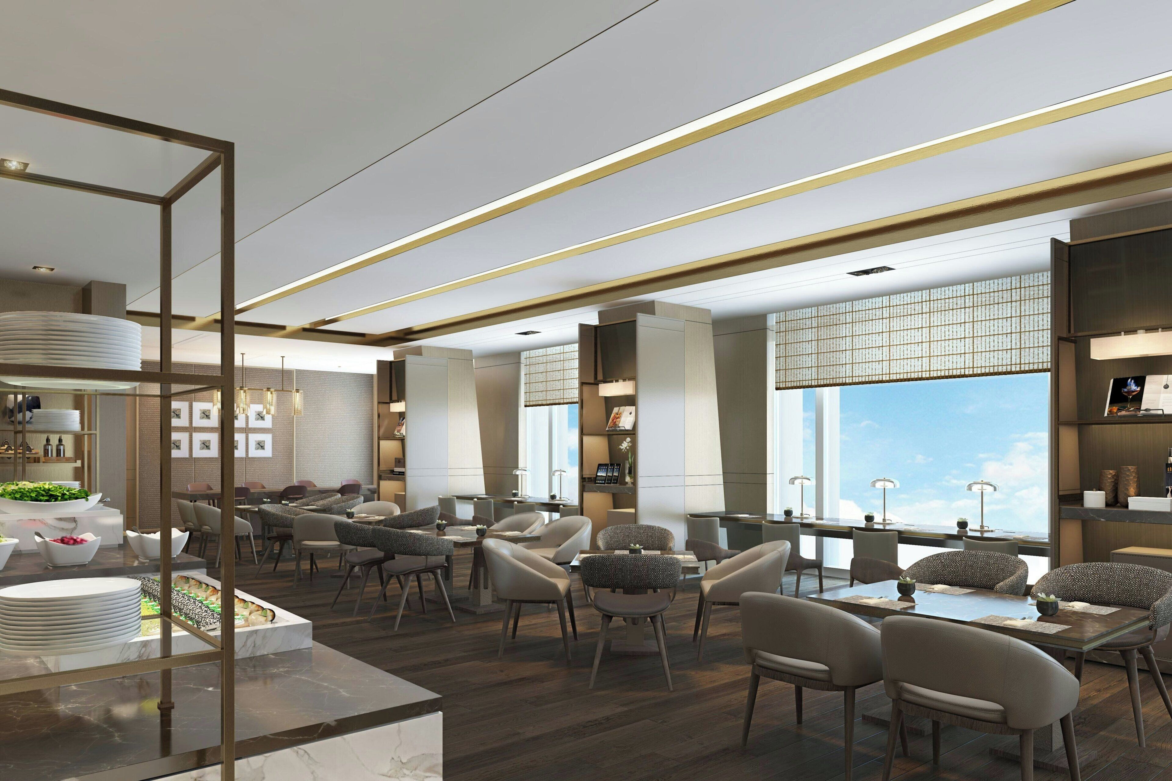 A modern hotel lobby with a dining area, large windows, and a view of the sky.