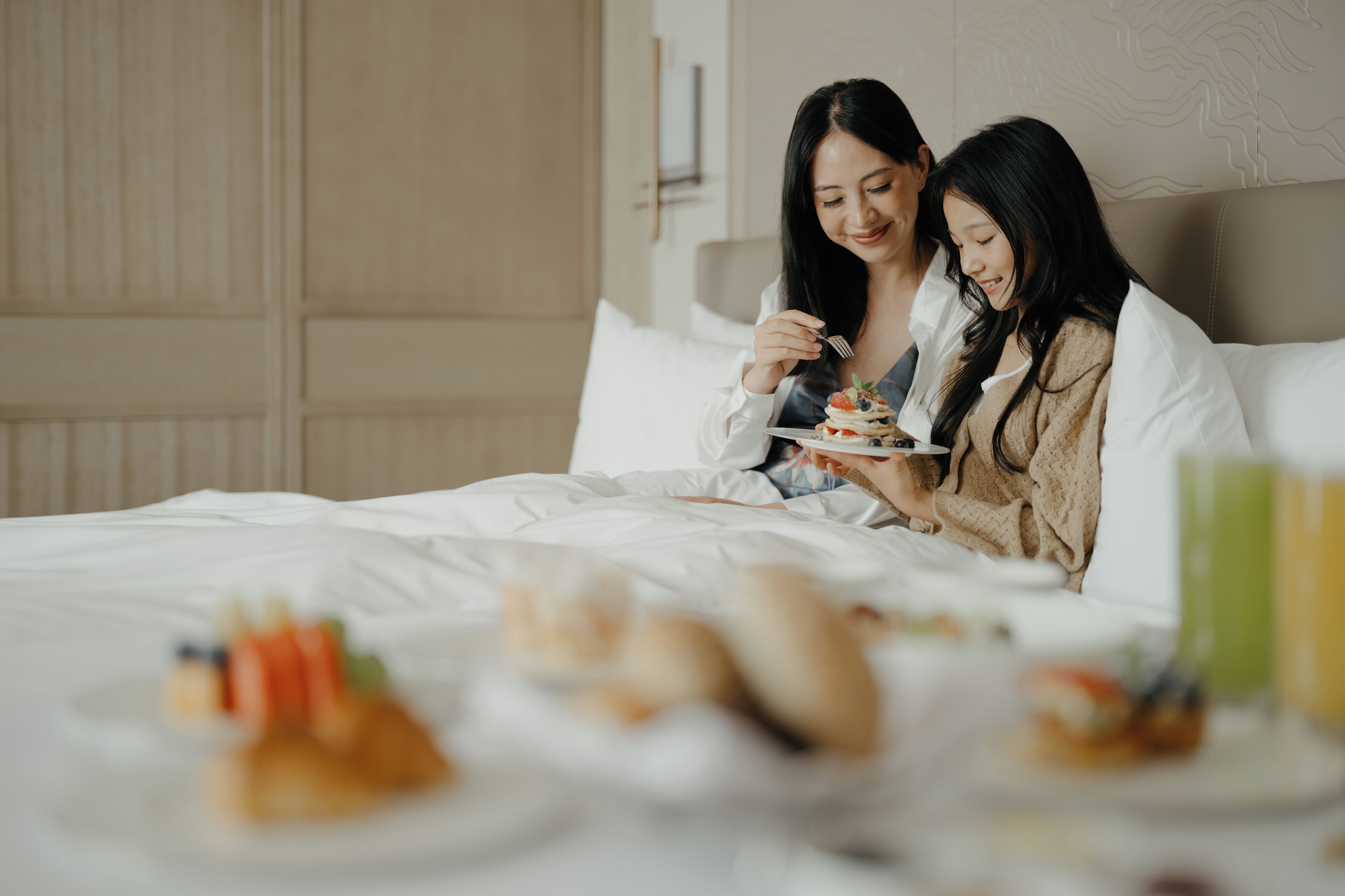 Habitación de hotel con cama, almohadas y una bandeja de desayuno con alimentos.