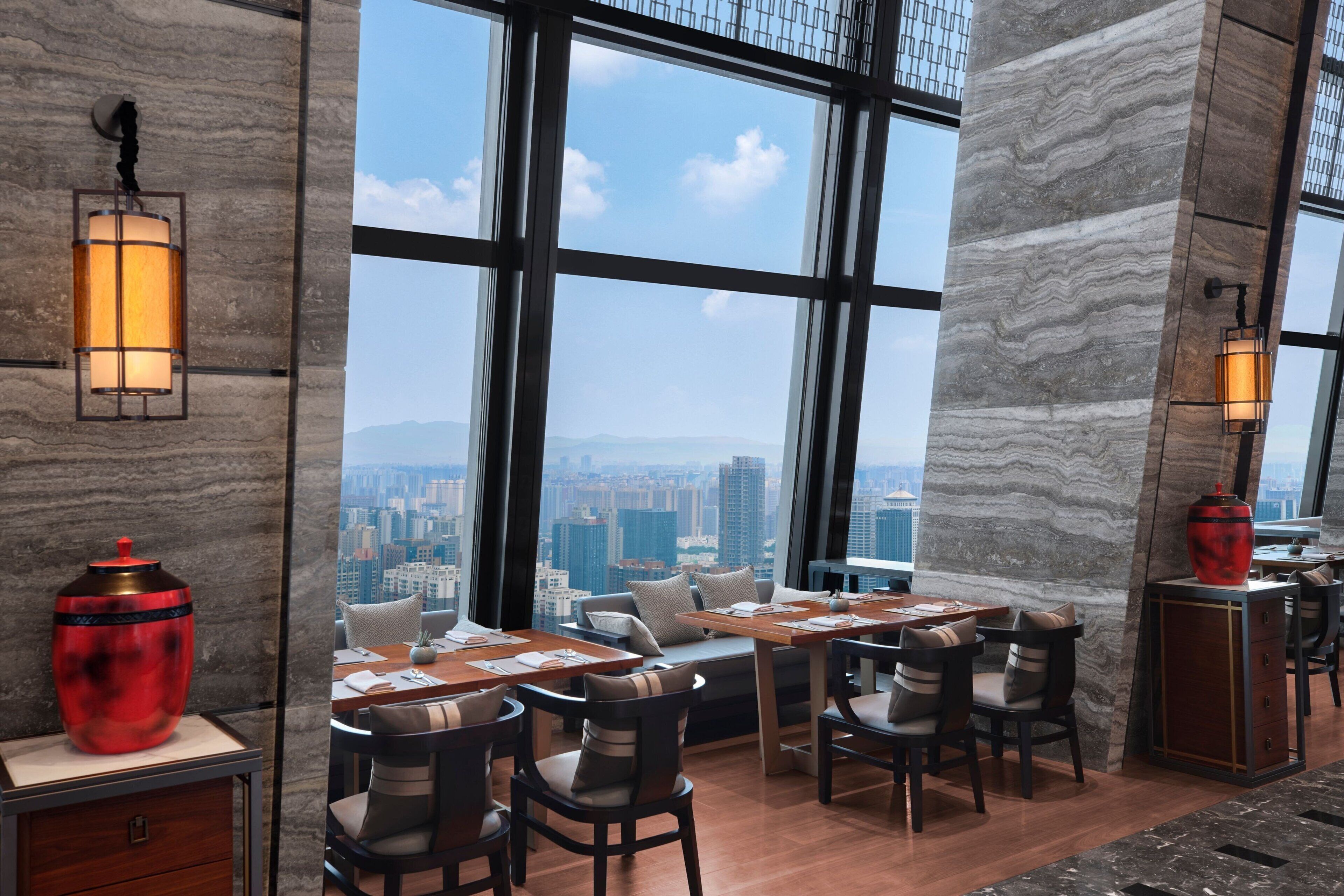 A modern dining area with a city view, large windows, and contemporary furnishings.