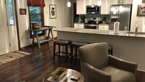 Una cocina moderna con una isla central, taburetes de bar y un comedor con mesa de madera.