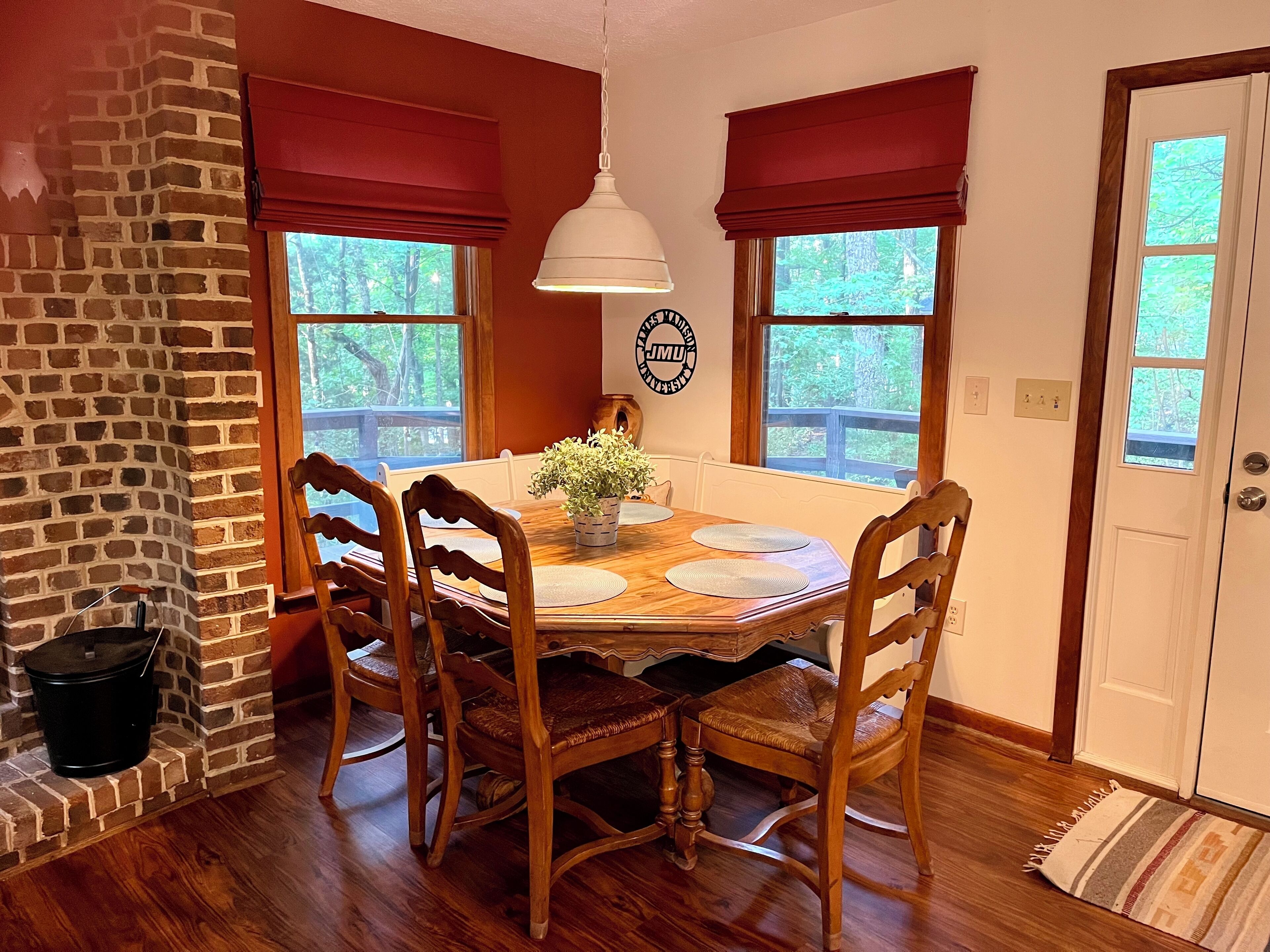A dining room with a brick fireplace, wooden dining table, and chairs.