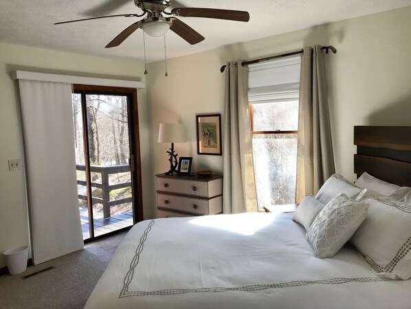 Un dormitorio con cama, ventilador de techo, cómoda y ventana con cortinas.