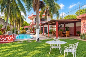 Un espace piscine doté d’un patio couvert, de coins salon extérieurs et d’une pelouse bien entretenue.