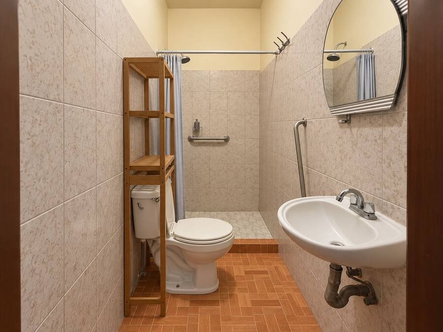 A bathroom with a toilet, a sink, a shower, and a mirror.