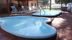 Ein Poolbereich mit zwei Whirlpools und Liegestühlen.