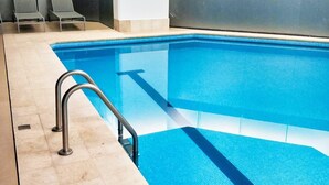 A swimming pool with a metal ladder, tiled floor, and two empty lounge chairs. - Two Beautiful 1 BR apts, 2 floors apart HS WiFi, full amenities! (Ciudad de México)