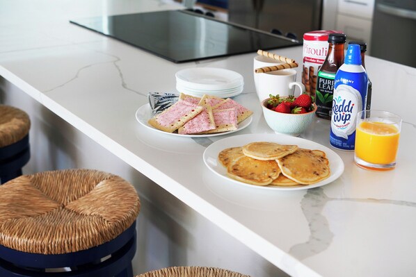 Una encimera de cocina con alimentos para el desayuno, como panqueques, fresas y café.