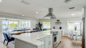 Una cocina moderna con armarios blancos, una isla grande y vistas al exterior.