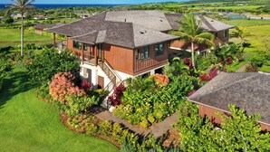 A large, two-story house with a spacious backyard, a staircase leading to the upper floor, and a view of the ocean.