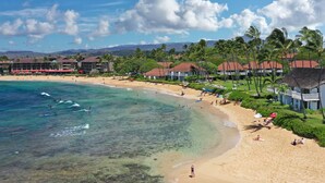 A beach resort with clear turquoise waters, palm trees, and a sandy beach.