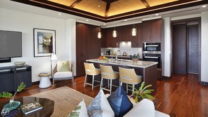 A modern kitchen with dark wood cabinets, a central island with bar stools, and a large island sink.