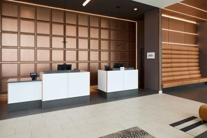 Ein Empfangsbereich im modernen Stil mit einer Rezeption, einer Sitzecke und einer Wand mit Rasteroptik.