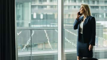 A person standing by a large window in a room with a view of a cityscape.