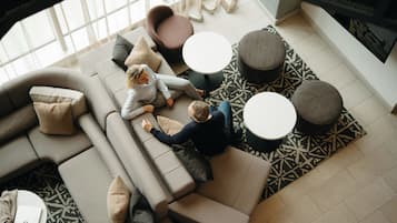 Uma sala de estar moderna com um sofá em forma de L, duas mesinhas de centro redondas e um tapete estampado.