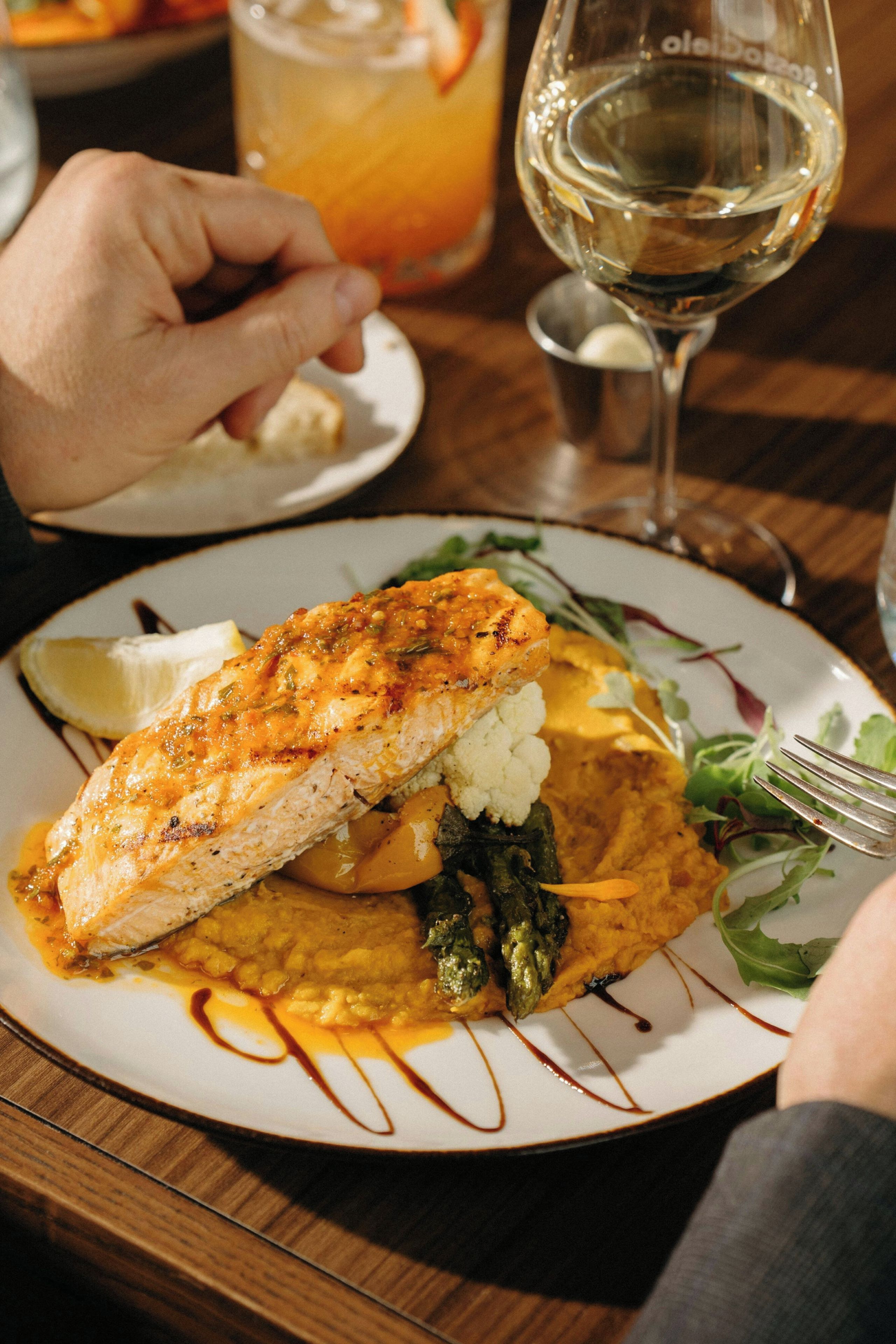 A plate of food with a piece of fish, vegetables, and sauce.